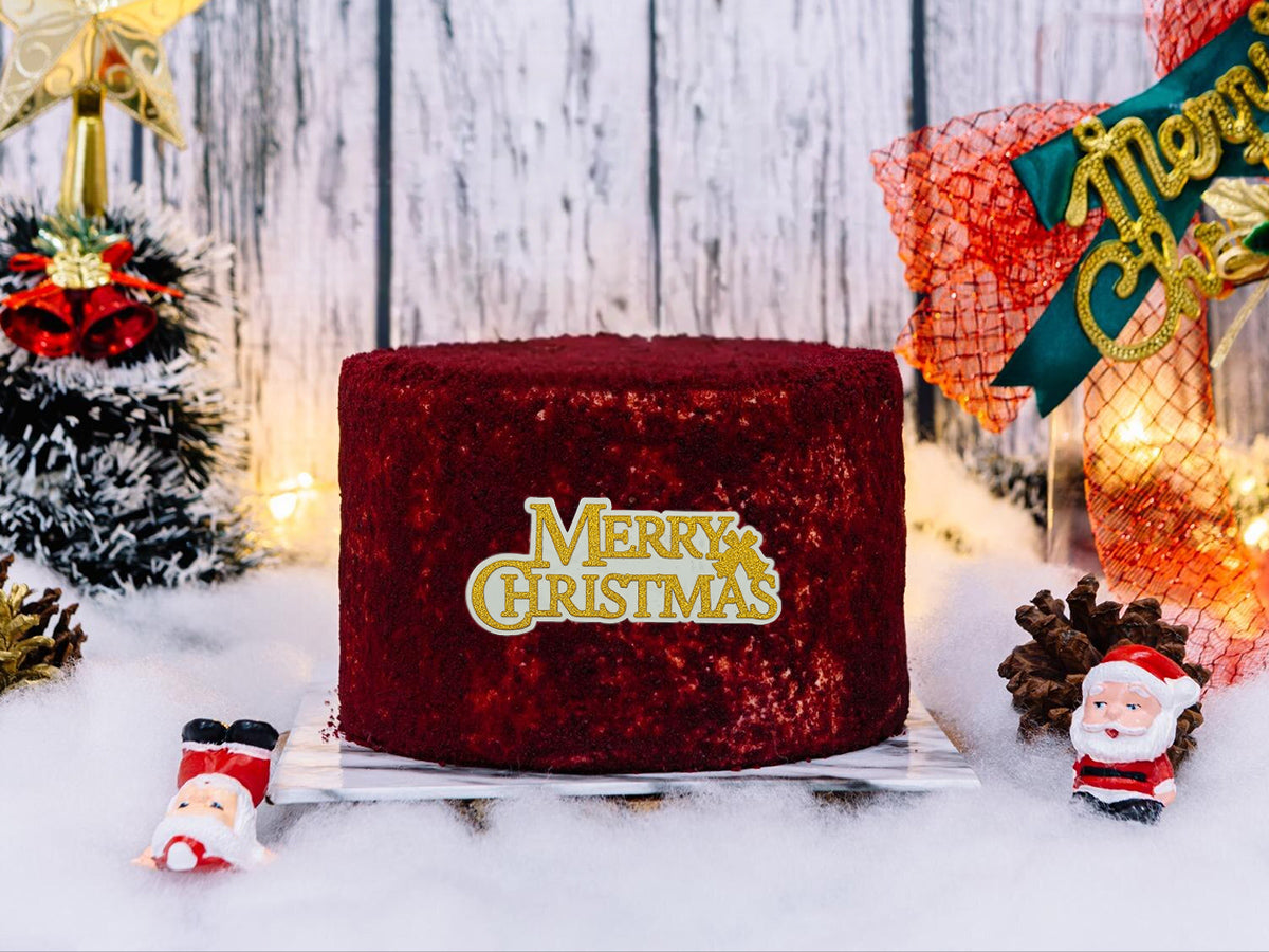 Red velvet cake with 'Merry Christmas' text in a festive setting with Christmas decorations.